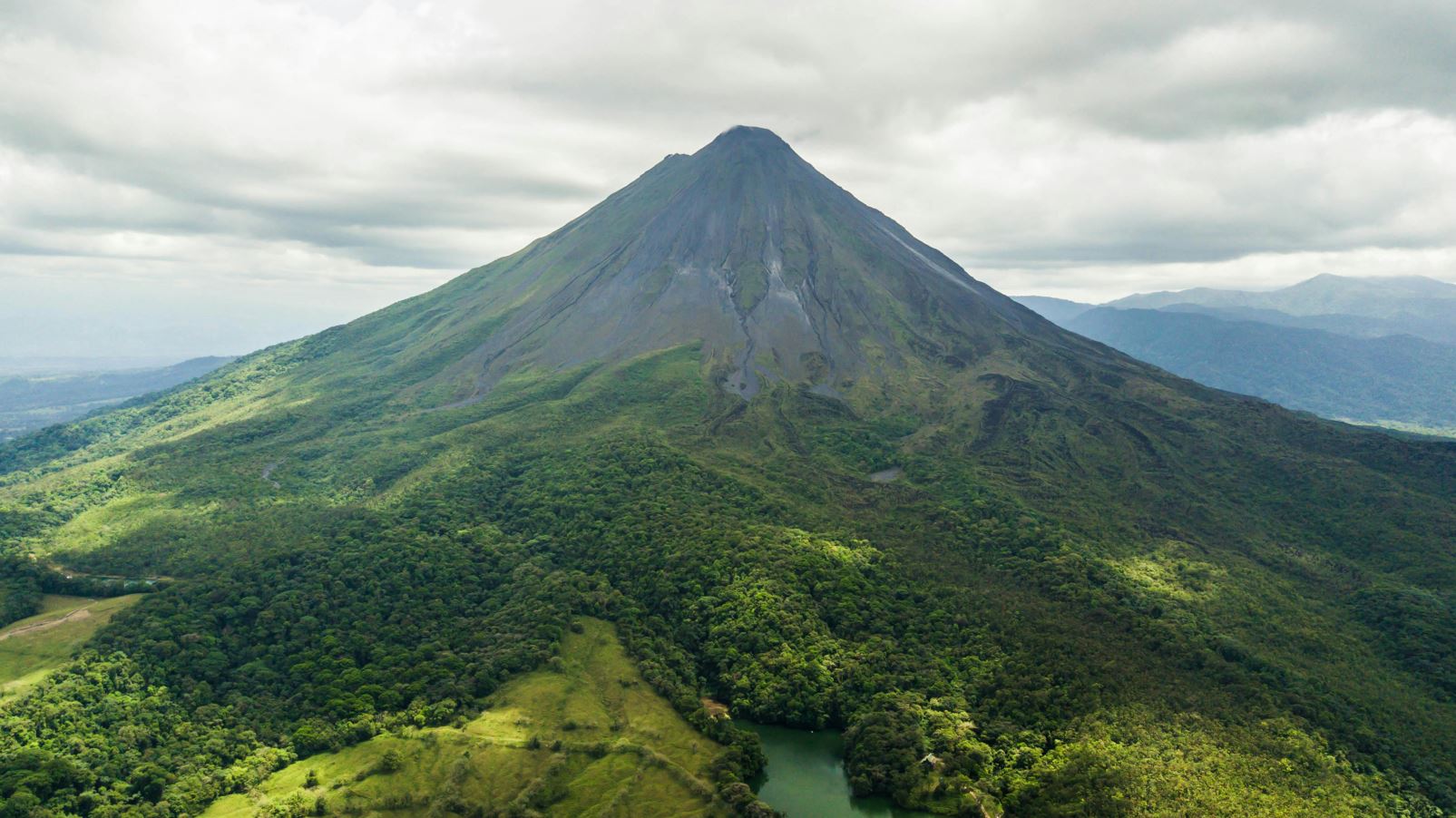 Arenal volcano seen from bird's eye view, with clouds and dense forest