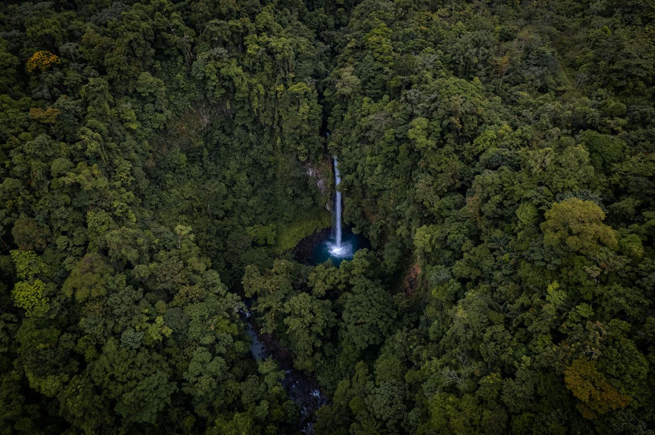 La Fortuna waterfall as seen from the air surrounded by the jungle and rainforest.